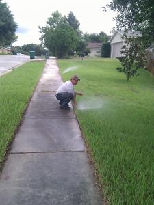 a tech adjusts a poorly aimed sprinkler head